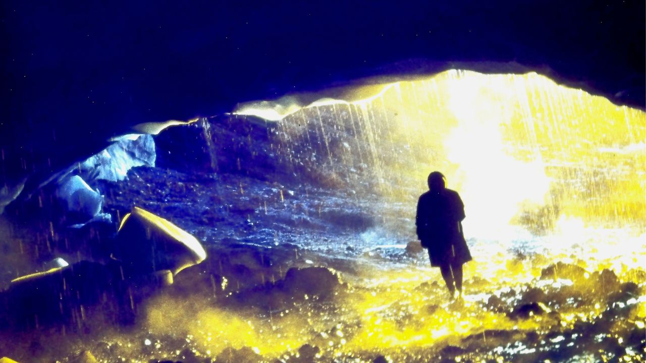 a person walking into a cave in the rain
